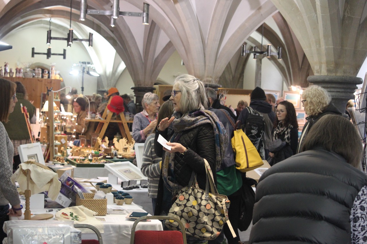 Image of people looking at craft stalls at the Christmas Artisan Market held in the medieval Bishop's Palace in Wells