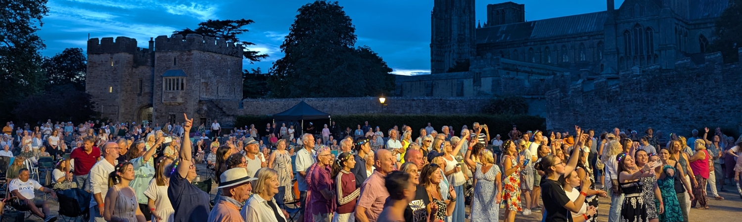 An image of a crowd enjoying live music at Party at the Palace at The Bishop's Palace in Wells, Somerset