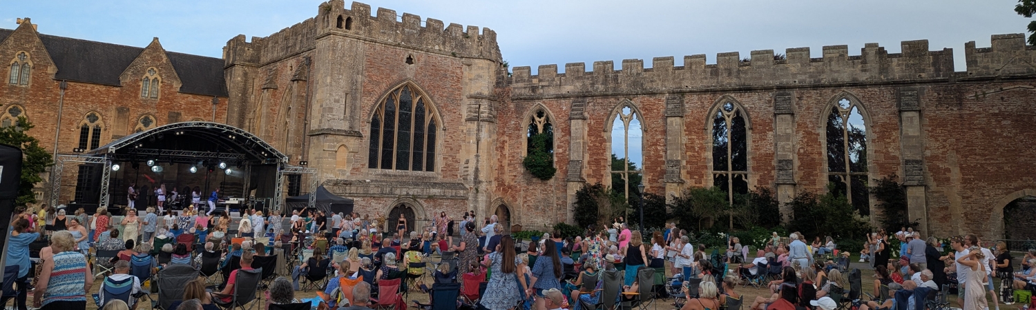 An image of a crowd enjoying live music at Party at the Palace at The Bishop's Palace in Wells, Somerset